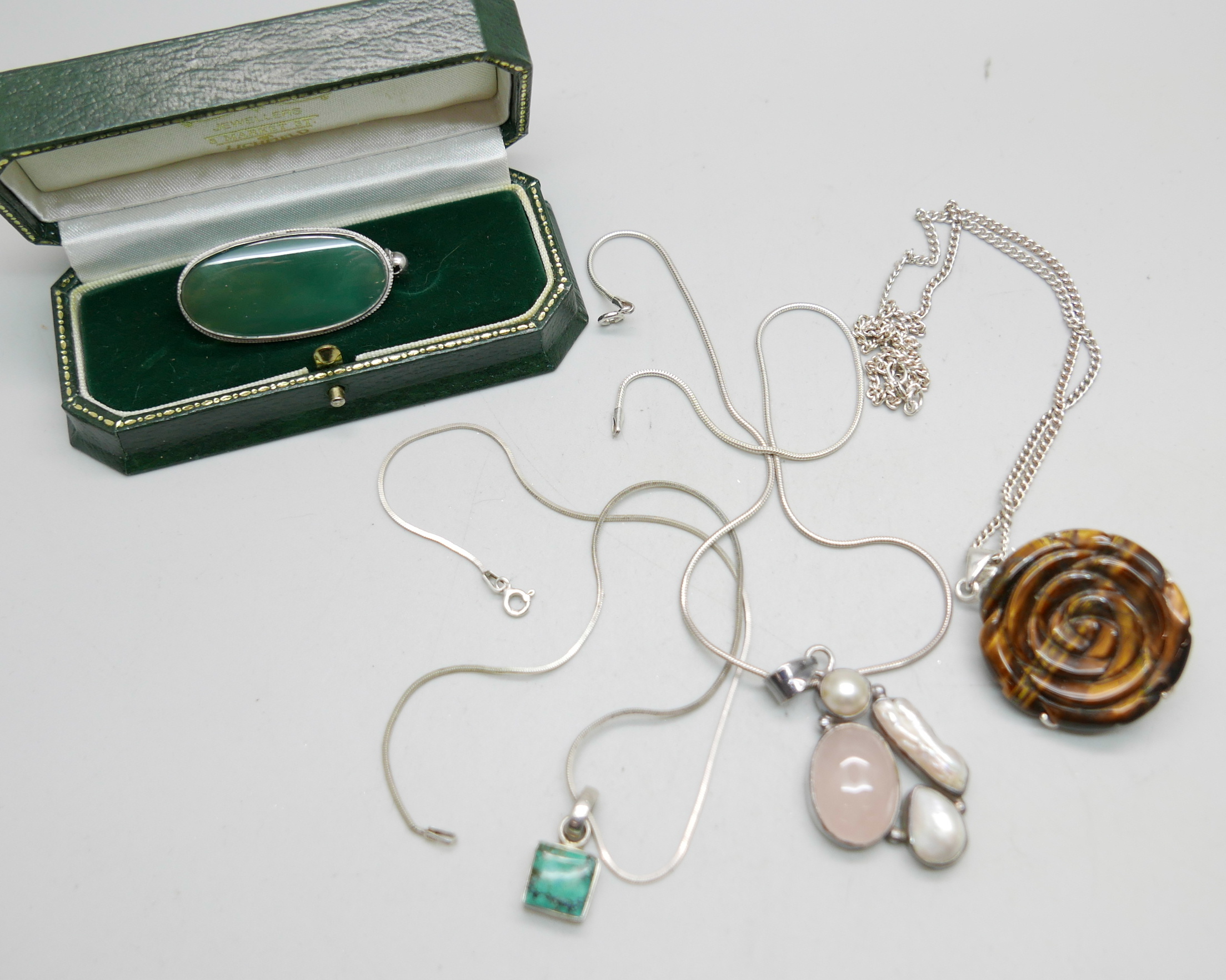 Three silver and gem set pendants and chains and a gem set brooch