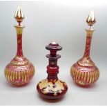 A pair of early 20th Century cranberry glass bottle with lids and gilt detail and a ruby glass scent