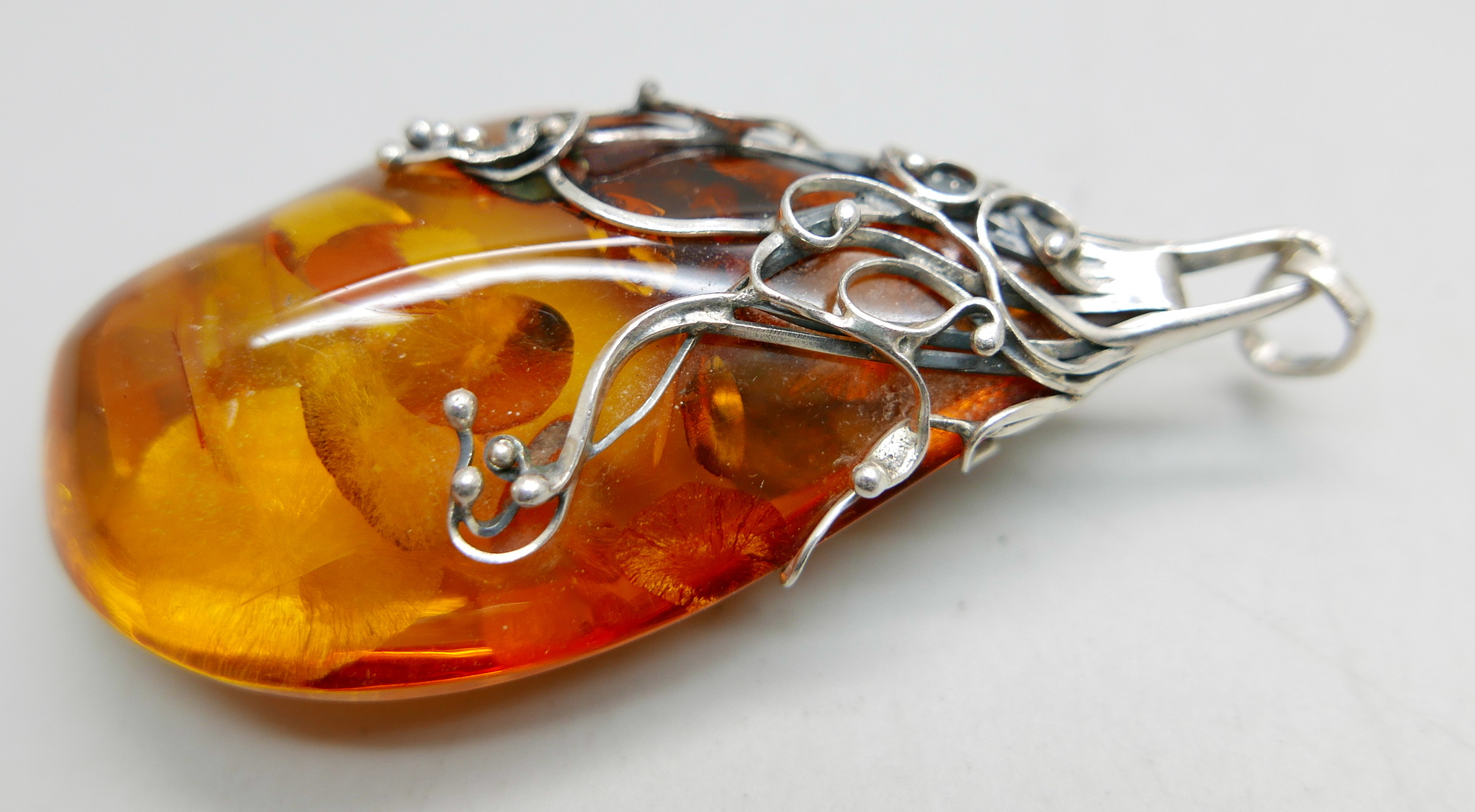 A large silver and amber pendant and chain, 9cm with the loop