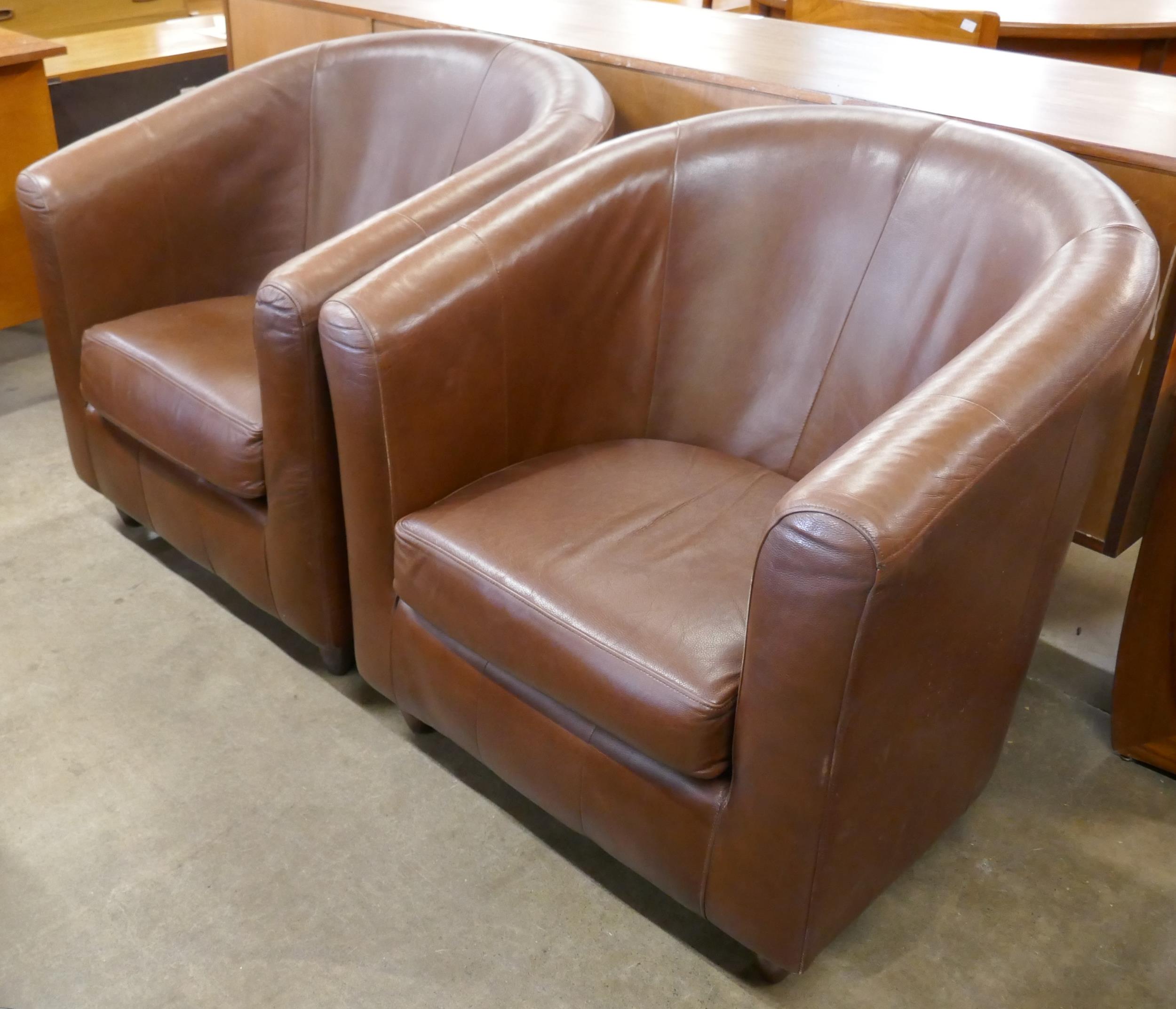 A pair of brown leather tub chairs