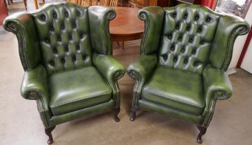 A pair of green leather Chesterfield wingback armchairs
