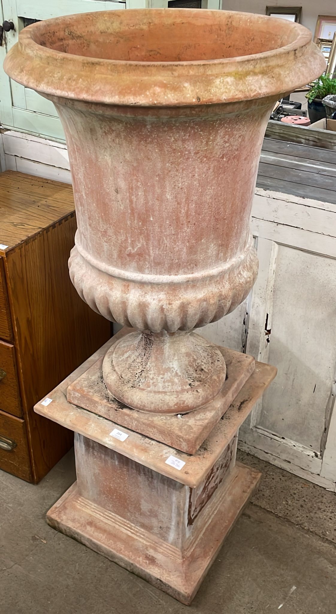 A large campana shaped terracotta garden urn on stand