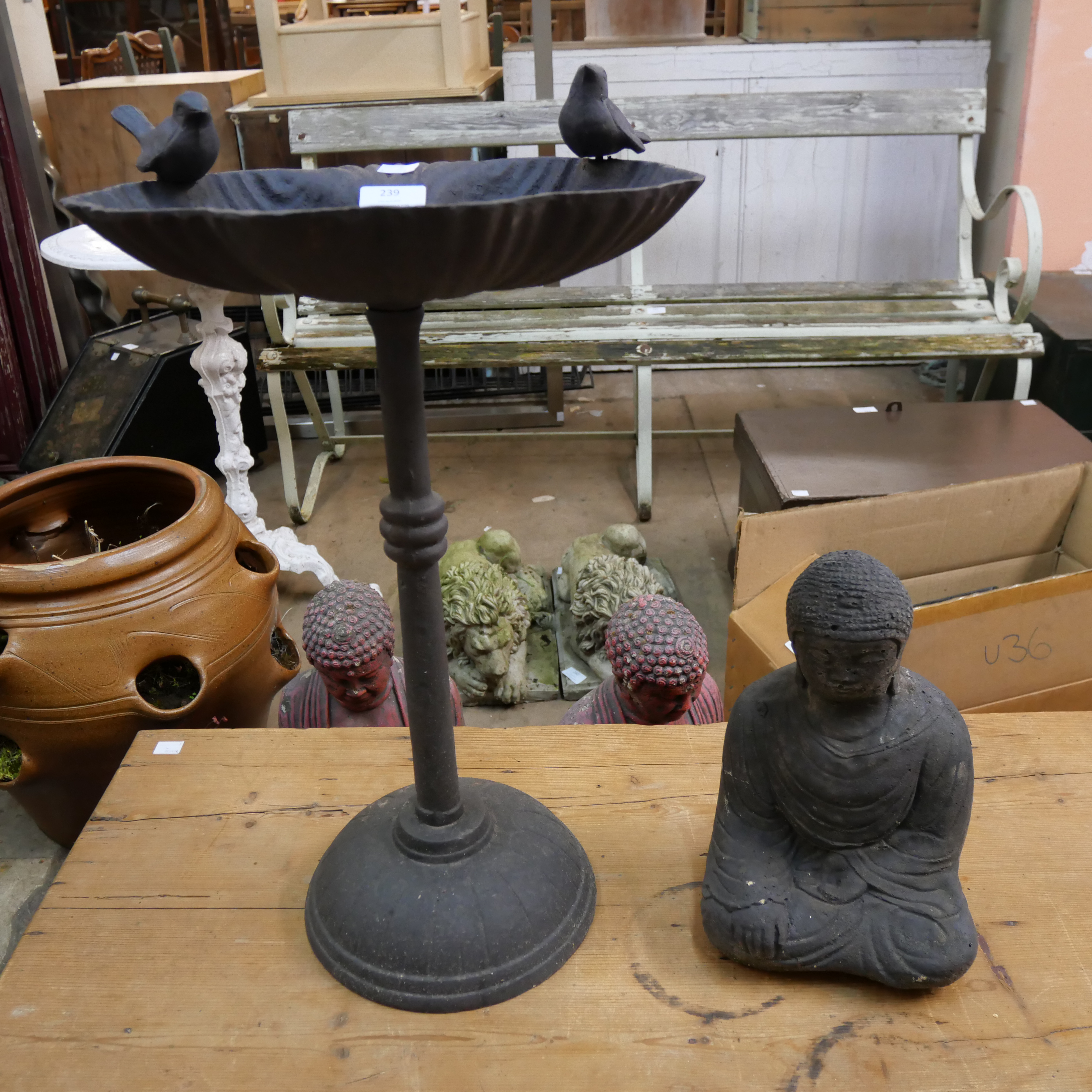 A cast iron bird bath and a stone figure of Buddha