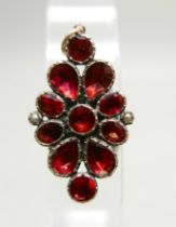 An early 20th Century yellow metal red stone and seed pearl set pendant, 19mm wide