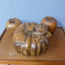 A large carved model of a pumpkin and two carved wooden lidded pots