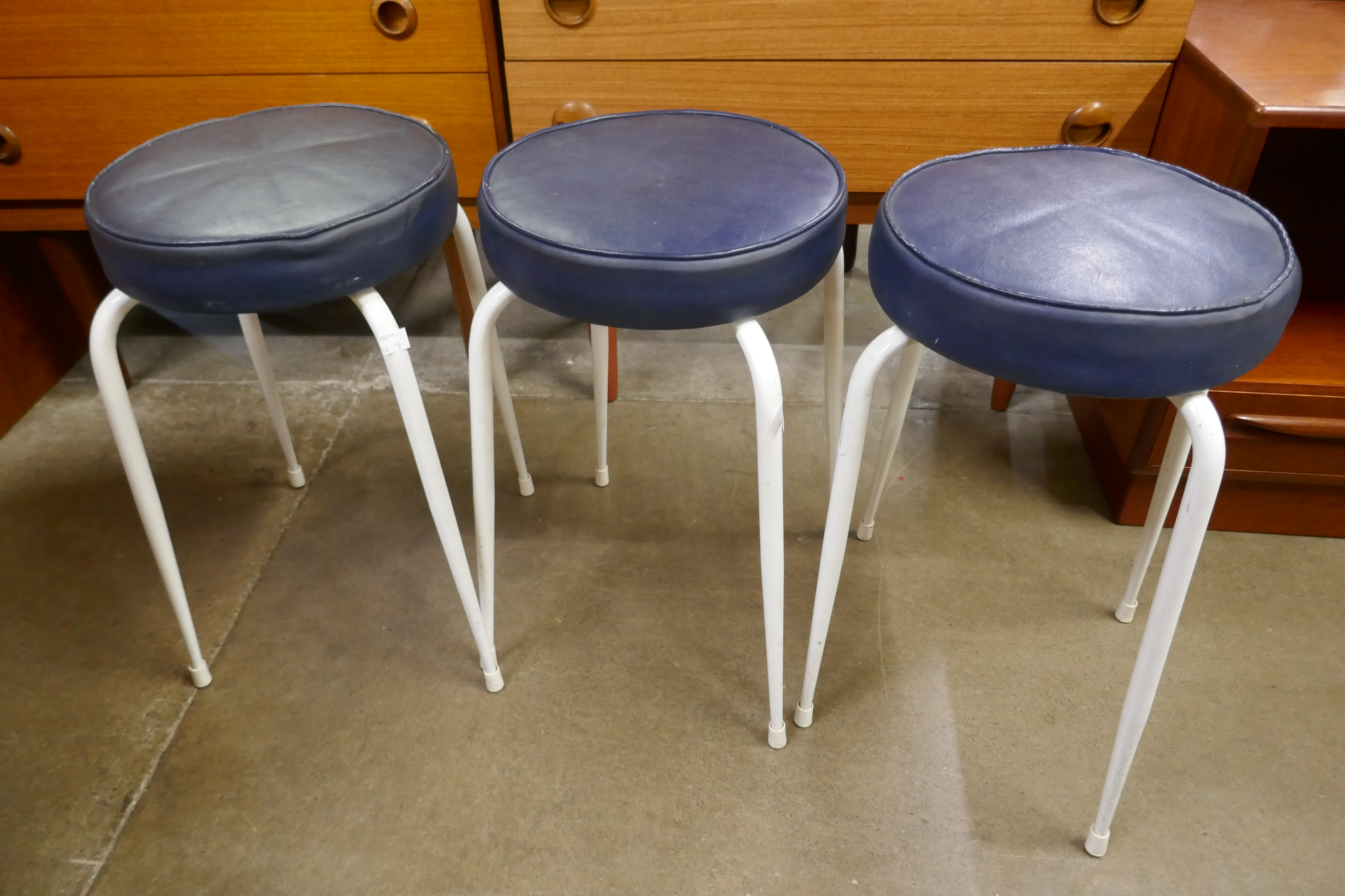 A set of three white tubular metal stacking stools