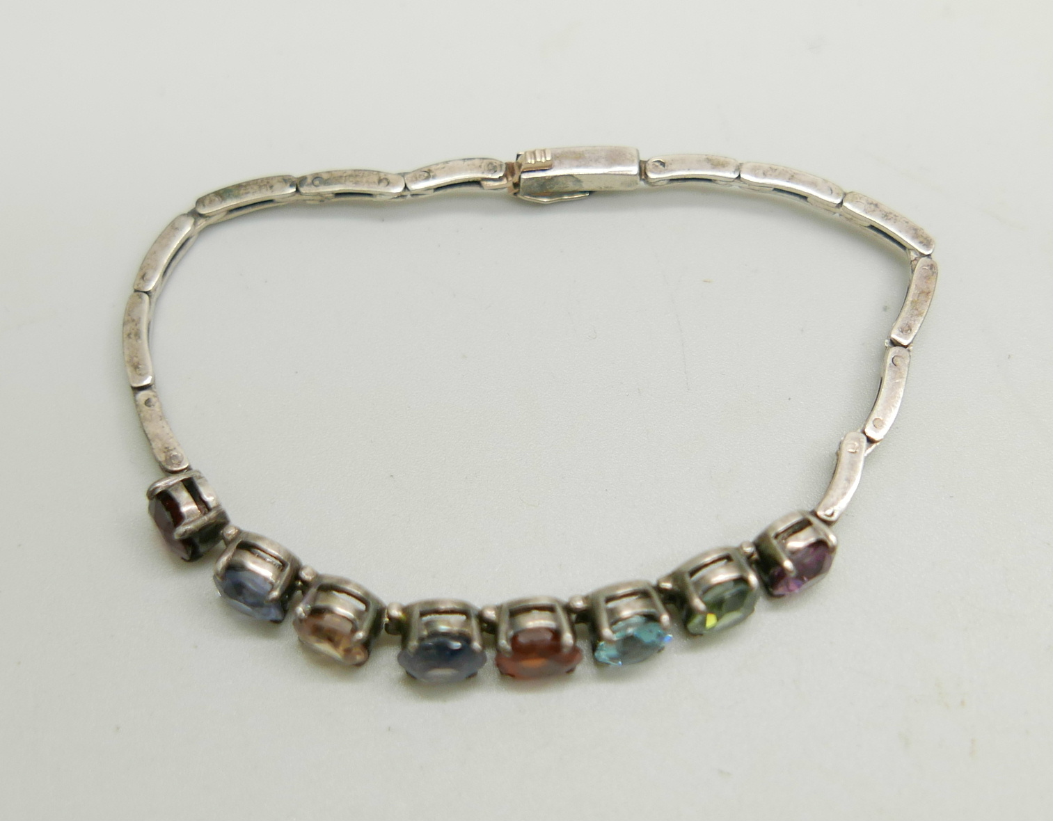 A white metal bracelet set with eight multi-coloured stones, 8g, approximately 16.5cm long