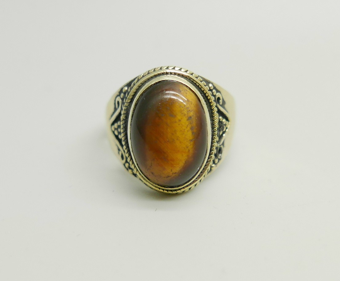 A silver gilt ring set with a cabochon tiger's eye stone, W