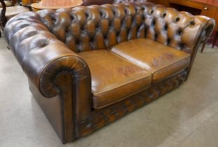 A chestnut brown leather two seater Chesterfield settee
