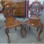 A pair of Victorian carved mahogany hall chairs