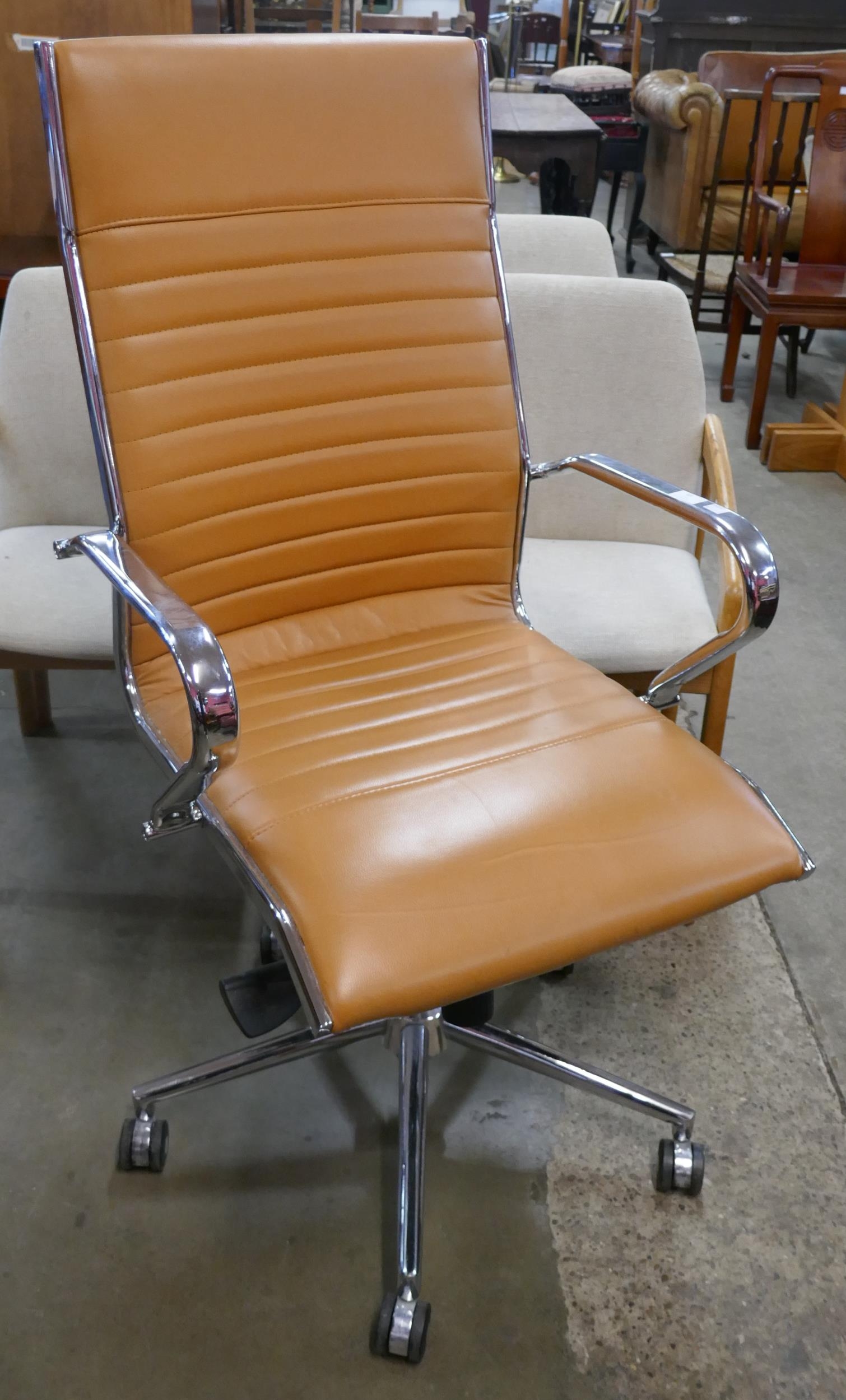 A Eames style chrome and tan leather revolving desk chair