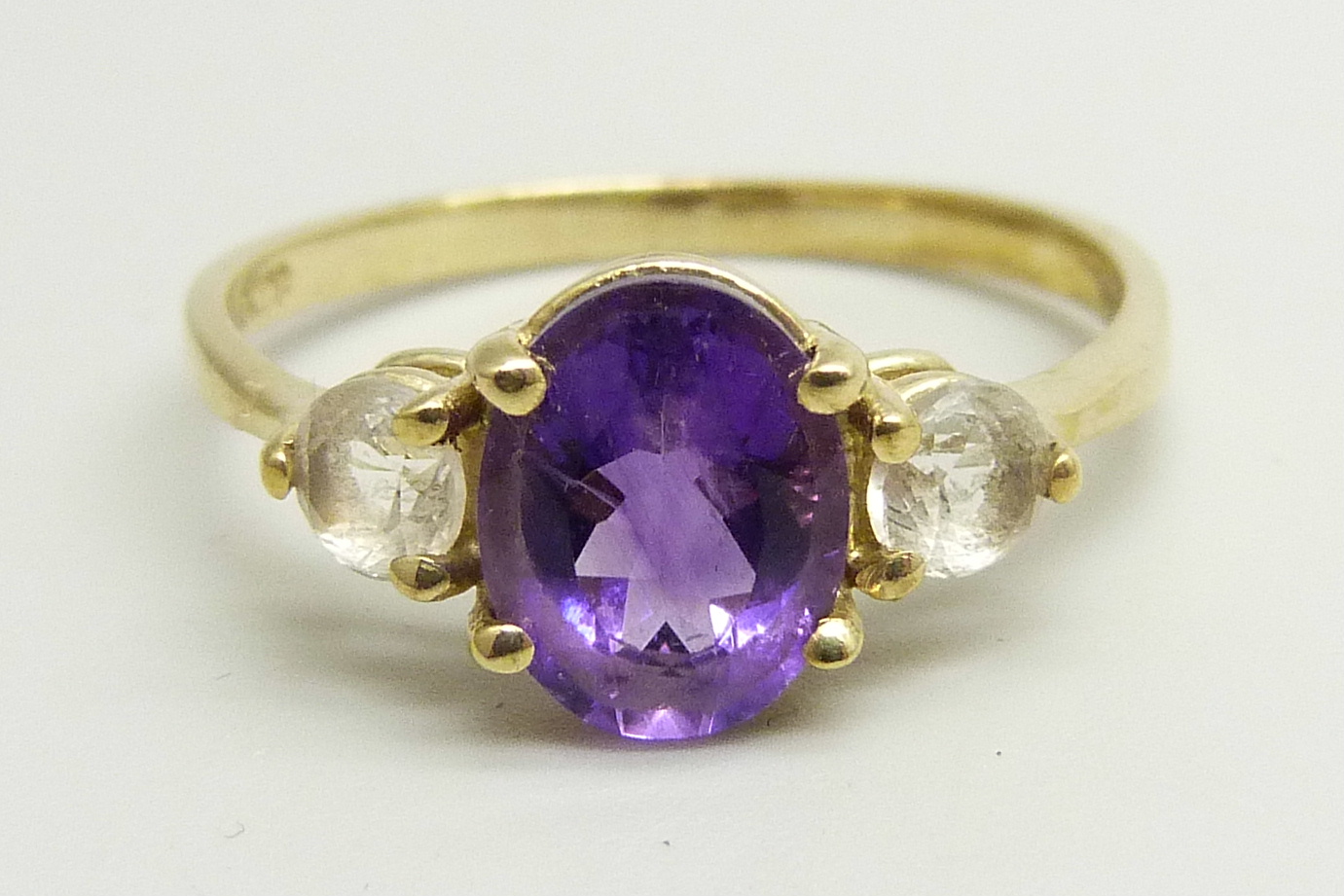 A 9ct gold ring set with a central amethyst and two white spinel, 2.8g, U