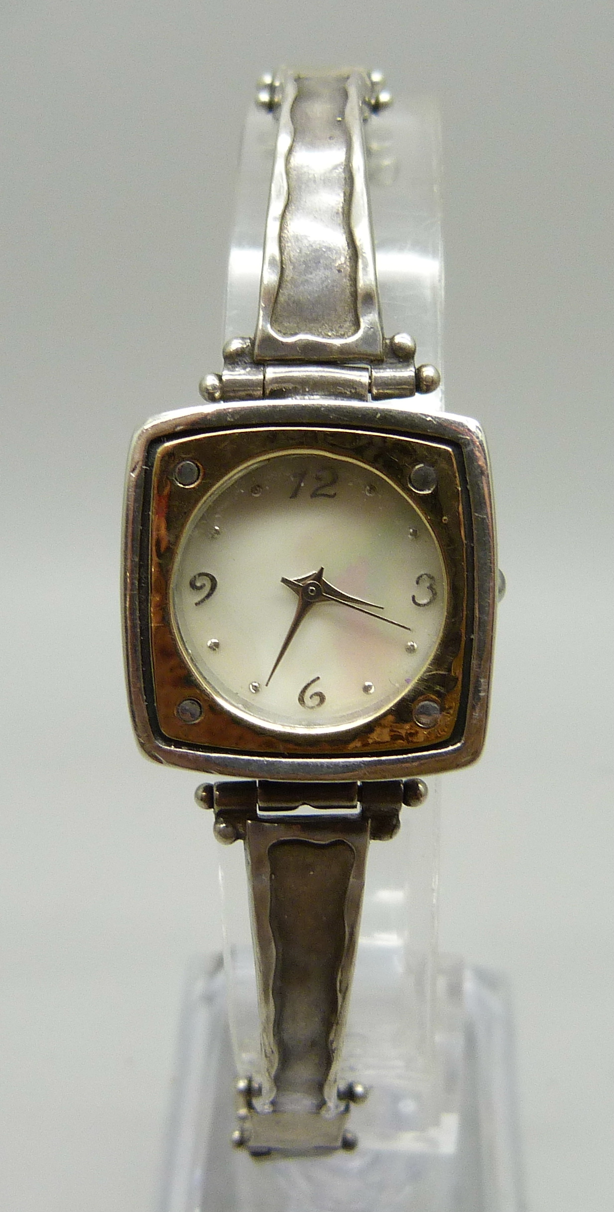 A lady's silver wristwatch with hammered design bezel and strap, hallmarked on the clasp with