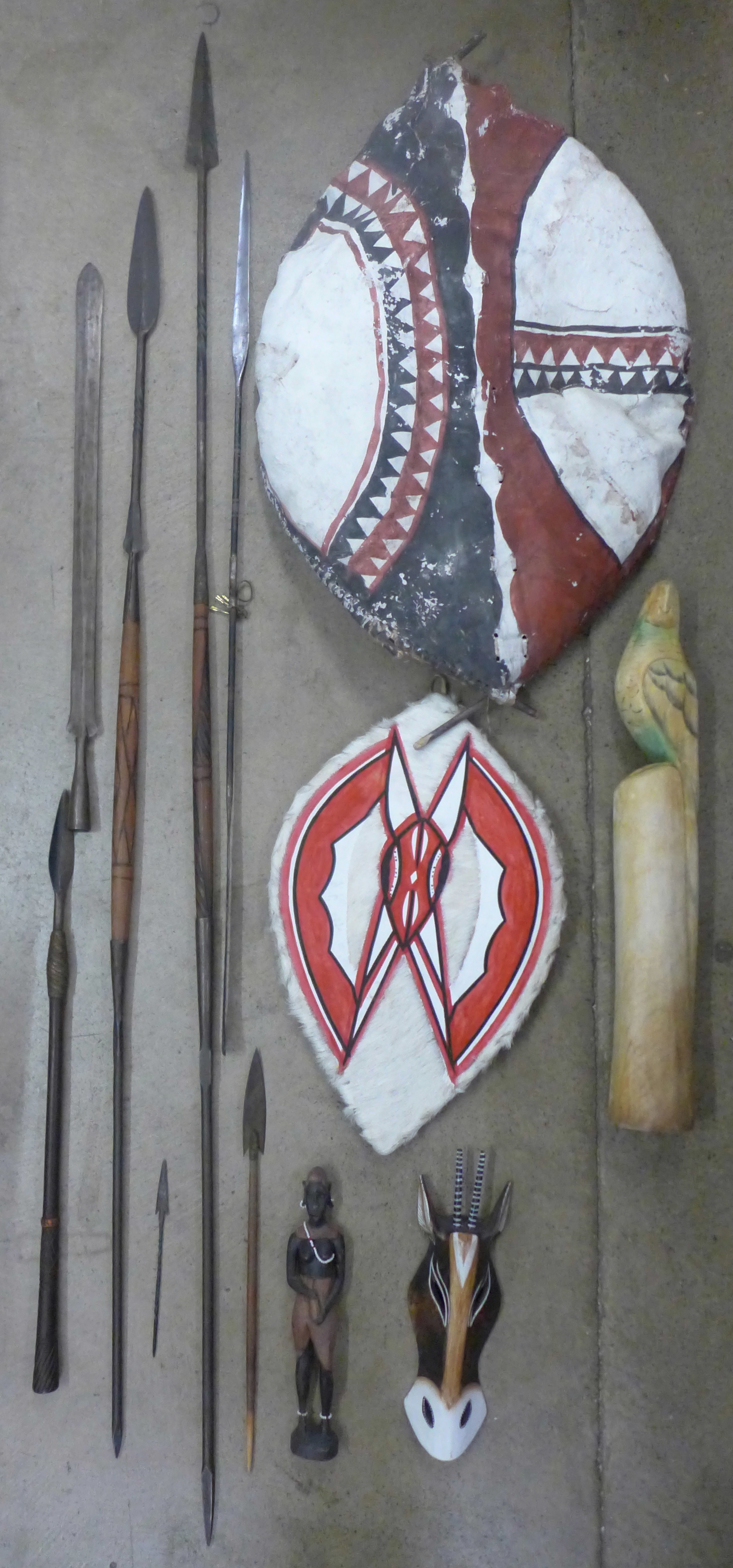 A collection of Maasai shields, spears, spear heads and wooden carvings, tallest spear 187cm