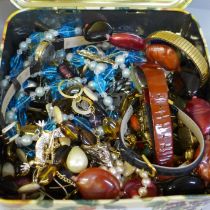 A tin of costume jewellery and wristwatches