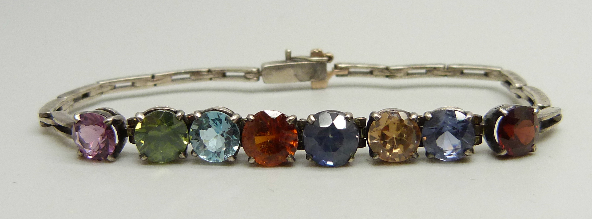 A white metal bracelet set with eight multi-coloured stones, 8g, 16.5cm long