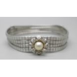 An articulated four row white metal bracelet with faux pearl centre flower fastener and safety