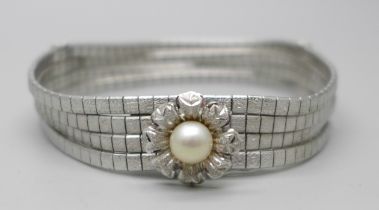 An articulated four row white metal bracelet with faux pearl centre flower fastener and safety