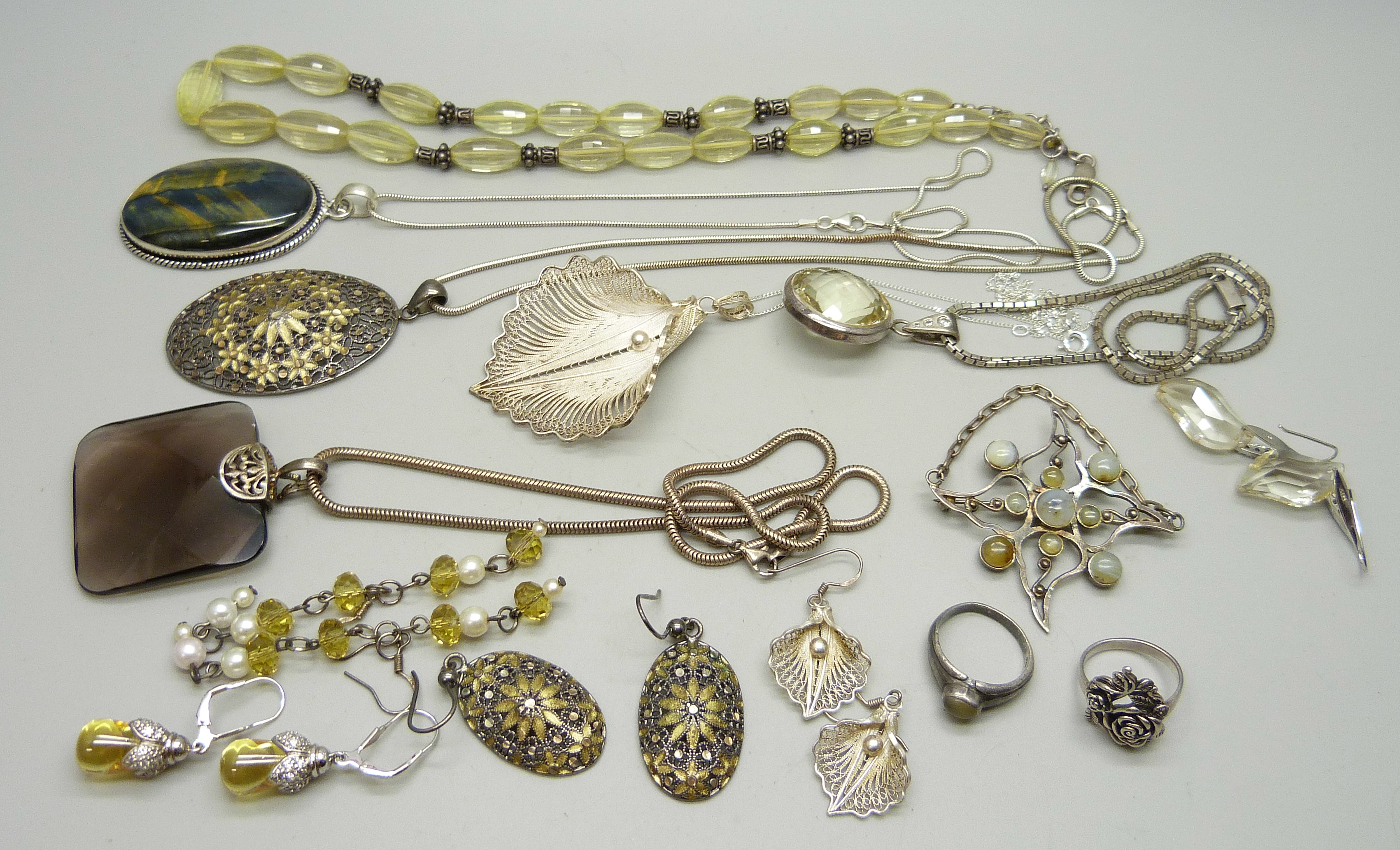A collection of silver jewellery including two filigree pendants, a citrine bead necklace and