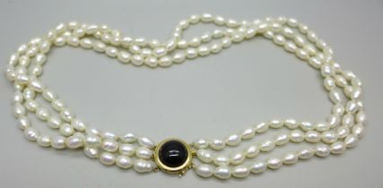 A three strand freshwater pearl necklace with a gold clasp marked 14K 585, 75g