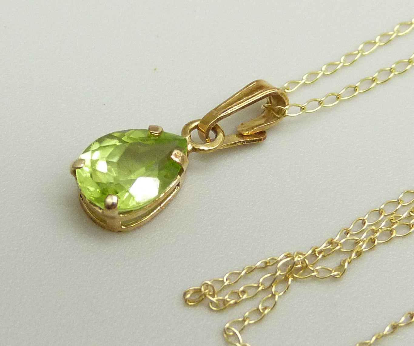 A 10k gold and peridot pendant on a fine 10k gold chain, 0.8g, chain approximately 46cm, pendant 1. - Image 2 of 3