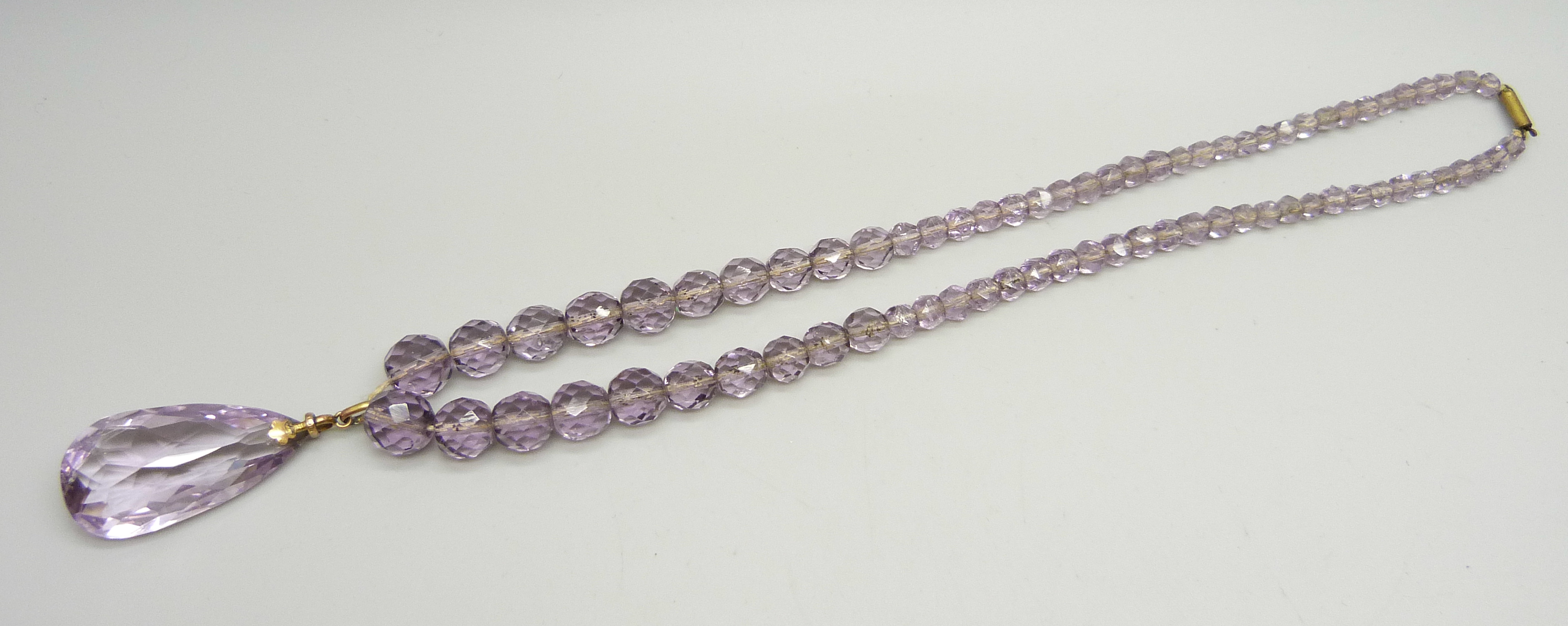 A faceted amethyst bead necklace, the bale marked 9ct, with a base metal clasp, 4.6cm pendant