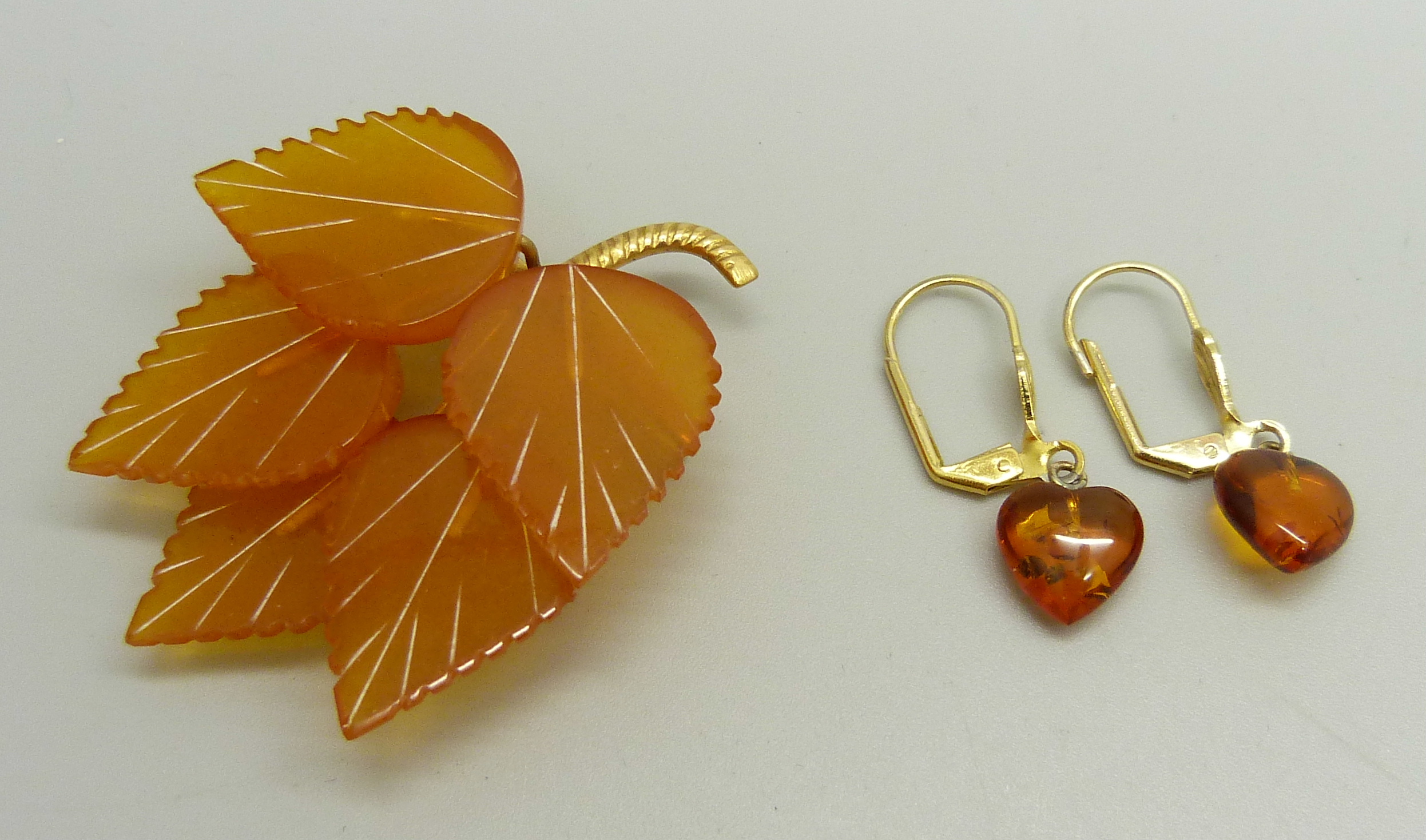 An amber coloured brooch in the form of a leaf and a pair of Baltic amber earrings