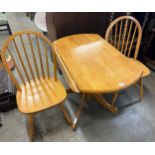 A beech drop-leaf kitchen table and two Windsor chairs