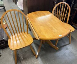 A beech drop-leaf kitchen table and two Windsor chairs