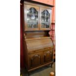 An Edward VII oak tambour bureau bookcase, with Art Nouveau stained glass doors