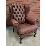 A chestnut brown leather wingback armchair