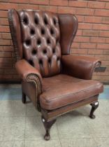 A chestnut brown leather wingback armchair