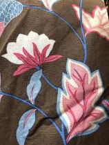 A pair of heavy curtains featuring a pink and blue floral and leaf design on a brown background,