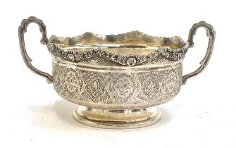 A Persian silver twin handled bowl, chased rim, the sides worked with intricate patterns, stamped '