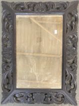 A carved oak rectangular wall mirror with foliate pierced frame and bevelled plate, 80x60cm