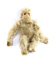 An early 20th century monkey doll, straw filled body with articulated arms, 33cmL