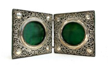 An Edwardian silver folding double photo frame, each roundel surrounded with pierced scrolls on a