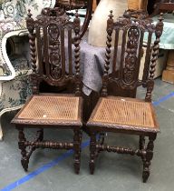 A pair of 20th century oak hall chairs, with carved backs and caned seats