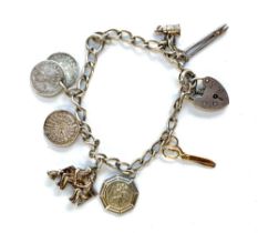 A silver charm bracelet with heart shaped padlock and a quantity of charms including yellow metal