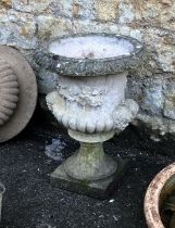A composite stone urn planter with twin mask lugs