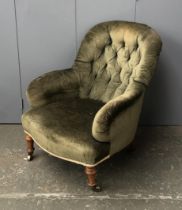 A Victorian button back armchair, on turned front legs with brass casters