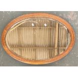 An oak framed oval mirror with bevelled glass, 85x59cm
