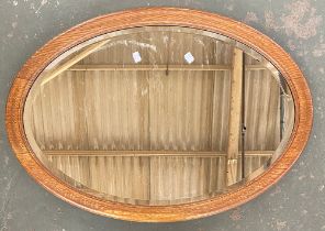 An oak framed oval mirror with bevelled glass, 85x59cm