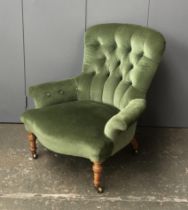 A Victorian low button back armchair, in green upholstery, on turned legs and casters, 77cmW