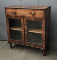 A Regency rosewood cabinet, beaded top over a single drawer and two glazed doors, on turned feet,