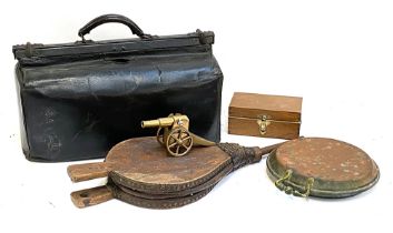 A black leather gladstone bag, together with fire bellows, brass model of a cannon, copper bed