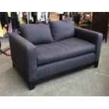 A contemporary two seater sofa, upholstered in a black pinstripe fabric, small holes in main cushion