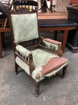 A carved oak armchair, floral detail to pediment top, upholstered in a green fabric, spindle
