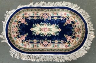 A large oval blue ground rug with floral design, approx 158x95cm
