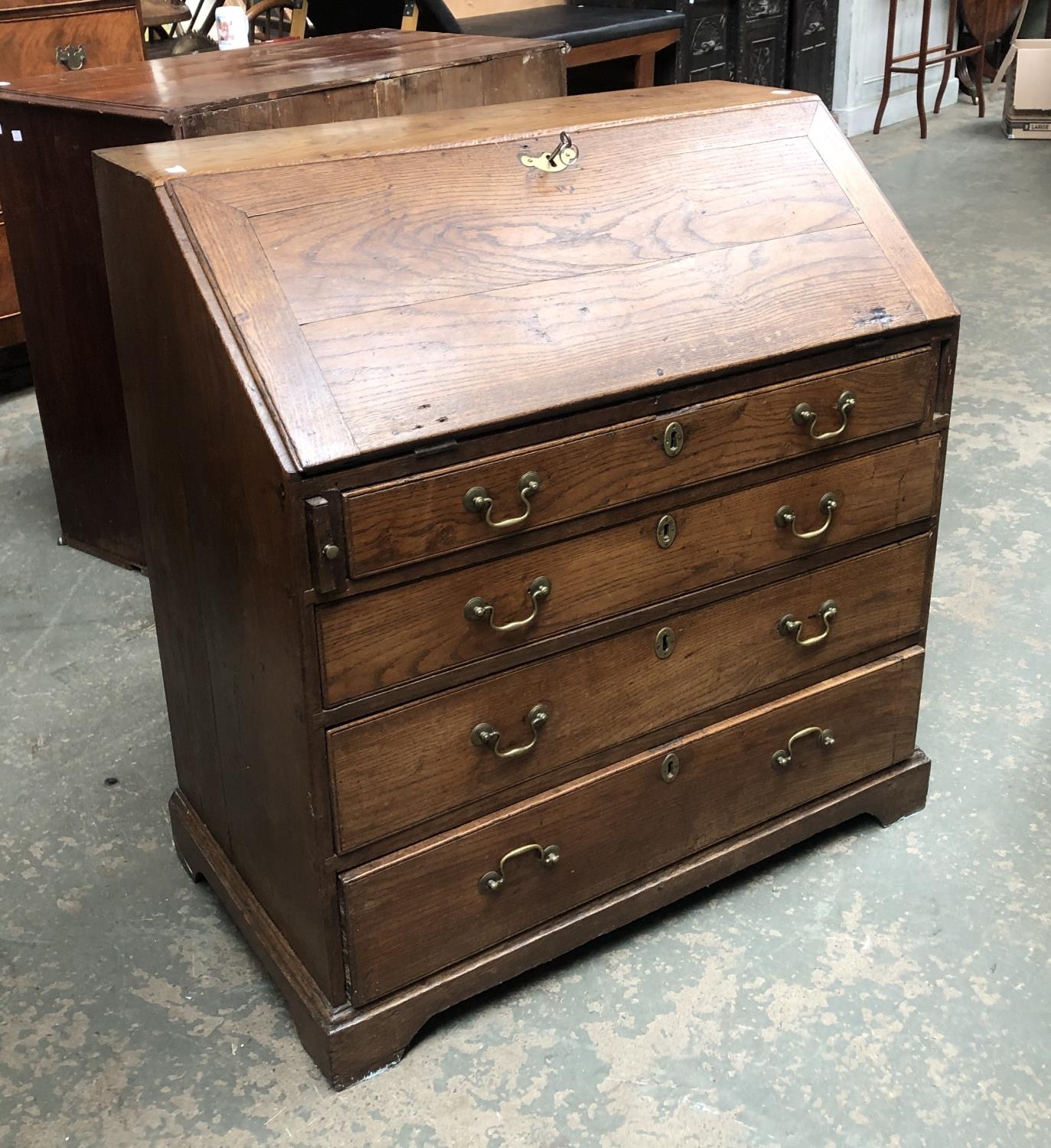 A George III oak bureau, the fall front opening to a fitted interior, over four graduating